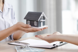 O femeie ofera un model la scara mica de casa inteligenta, evidentiind sisteme de supraveghere si automatizare.