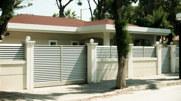 O casa frumoasa cu un gard alb si o poarta alba, dotata cu un sistem de automatizare pentru confort sporit.