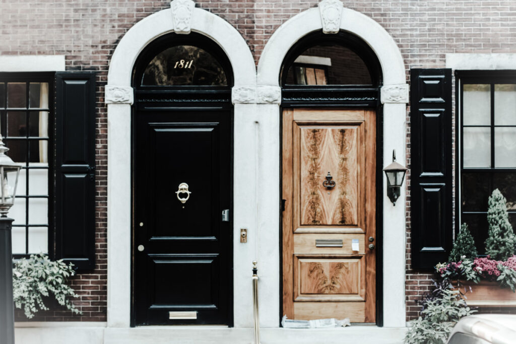 Doua usi la o cladire din caramida, cu camere de supraveghere tip vizor montate pe perete.