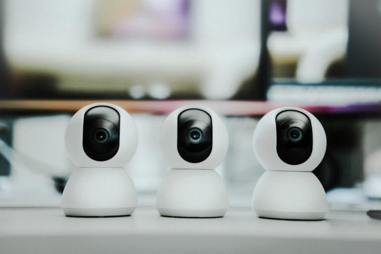 Trei camere de supraveghere inteligente pentru acasa, asezate pe un birou, oferind siguranta si monitorizare eficienta.