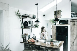 Intr-o bucatarie moderna, o femeie se bucura de moment, avand o electrovalva de apa alaturi.