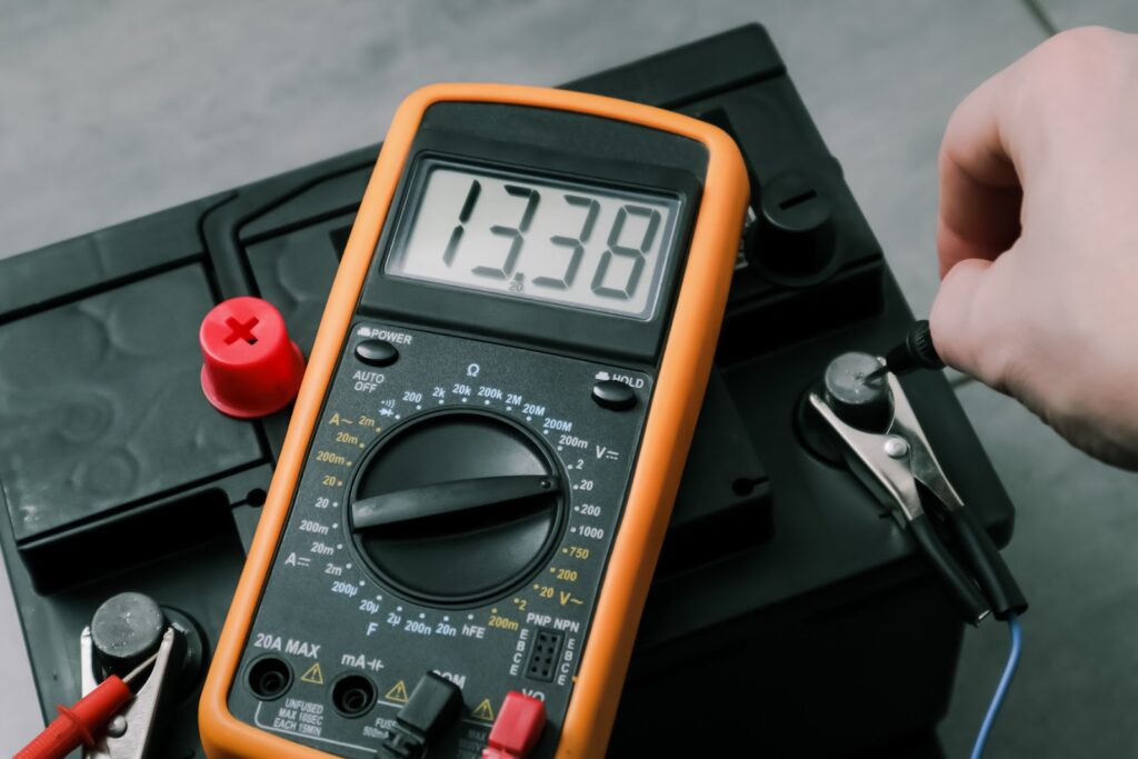 O persoana folosește un multimetru pentru a verifica frecventa puterii unui UPS, parte a unui sistem de supraveghere video.